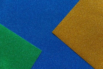 Green,gold and blue sparkling background from small sequins, closeup. Shimmer paper