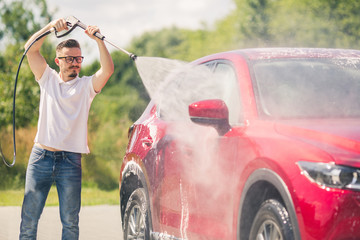 Wall Mural - Manual car wash with pressurized water in car wash outside. Summer Car Washing. Cleaning Car Using High Pressure Water. Washing  with soap. Close up concept.