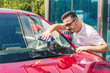 © Oleksandr Kozak - Car detailing - the man holds the microfiber in hand and polishes the car. Selective focus. Car detailing series : Worker cleaning red car.