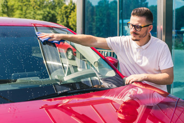 Wall Mural - Car detailing - the man holds the microfiber in hand and polishes the car. Selective focus. Car detailing series : Worker cleaning red car. 