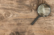 Magnifying glass on old wooden table background. With space for design, text place.