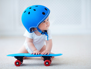 cute infant baby girl in protective helmet outfit ready to ride skateboard, extreme sport concept