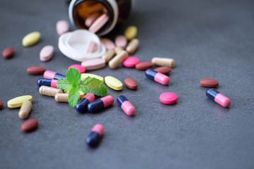 Assorted pharmaceutical medicine and herbal arganic medicine capsules on table dark background.