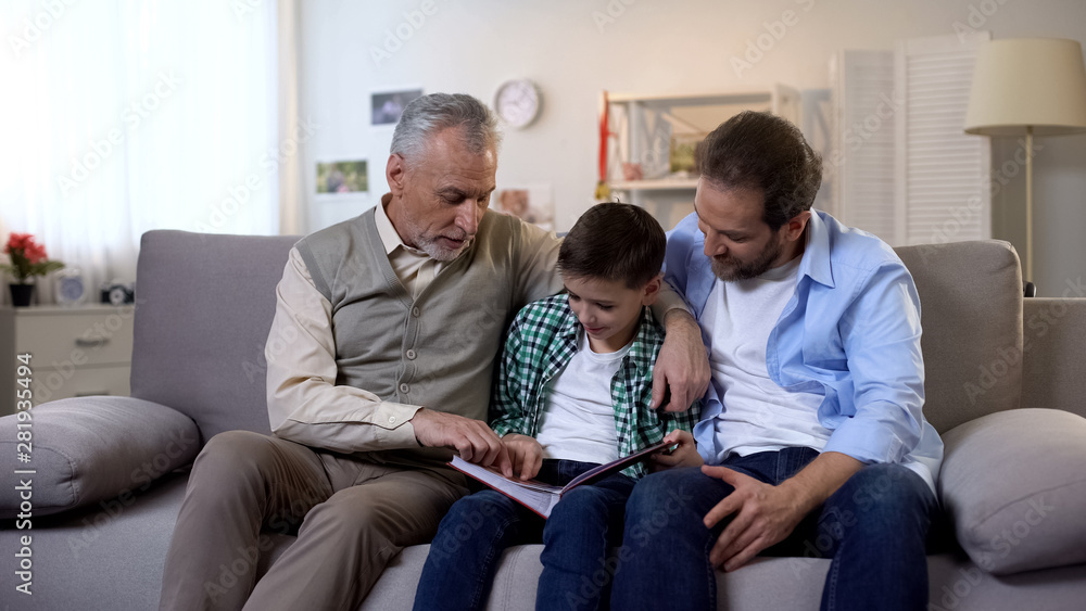 Happy grandpa, adult son and grandson viewing photos in album together, memories - obrazy, fototapety, plakaty 