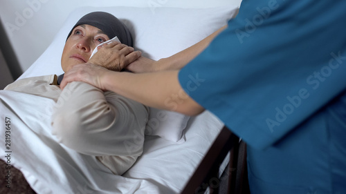 Fotografía Doctor supporting crying female patient suffering cancer, wiping tears on face