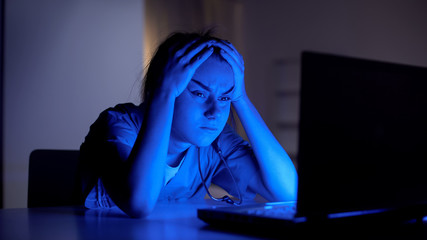 Tired young doctor working on computer at night, preparing for examination