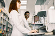 © sofiko14 - Two pharmacists man and woman checking information about medicines on the computer together, modern pharmacy