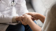 © fizkes - Close up horizontal image doctor holding hands of female patient