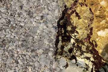 Clear water of the Ionian Sea with white pebbles and brown rock