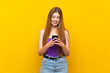 © luismolinero - Young woman over isolated yellow background sending a message with the mobile