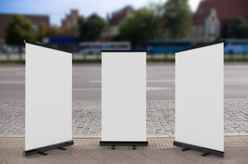 Wall Mural - 3D rendering of blank vertical rollup (empty billboard advertisement) with city background. Empty mockup template