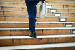 © SUPERMAO - A businessman carrying a work bag is walking up the stairs to the office.