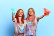 © alfa27 - cheerful awesome funny female friends throwing colorful powder at holi festival. isolated blue background, studio shot. great time