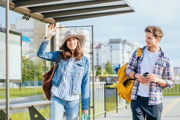 people student traveling concept. couple traveling together standing at bus station, waiting for tra