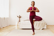 © Anatoliy Karlyuk - Horizontal shot of attractive flexible young dark-skinned female wearing leggings and top holding hands in front of her chest in namaste, doing vriksasana pose. Cute black girl doing tree yoga stance