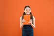 © be free - Childrens literature. happy little girl with notebook. literature lesson. school girl read book on orange background. poetry and novel. modern education. writing notes. kid diary. back to school