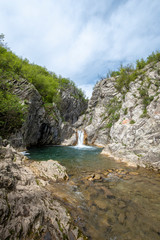 Blue Sini vir waterfall at Medven, near Kotel, Bulgaria. Spring green view of a beautiful waterfall among cliffs. Emerald lake and blue sky landscape