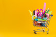 Shopping cart with School stationery on yellow background.