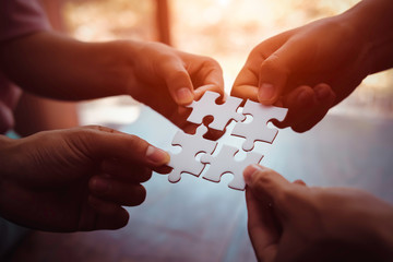 closeup hand of business people connecting jigsaw puzzle with sunlight effect, business solutions an