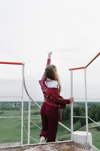 Girl In Red Clothes Stands On A Lighthouse With Her Hand Raised Up