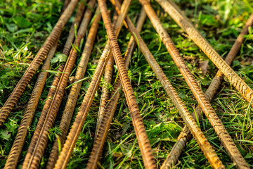 rusty long reinforcement construction pattern many pole metal on grass background close-up