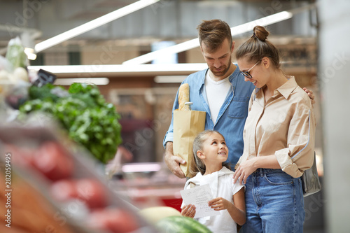 Portrait of happy young family shopping for groceries at farmers market, copy space