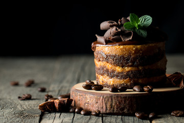 Chocolate cakes on black slatter board with mint, coffee beans on dark background, closeup photo. Fresh, tasty dessert food concept.