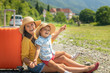 © Alex Desanshe - Happy family in the summer goes to rest, on vacation: mother and son with a suitcase on the background of nature and mountains