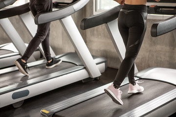 Close up shoe group of young  people walking on treadmills warm up in sport gym  . two fitness woman runner on running machine in morning time . workout .training . exercise. healthy lifestyle