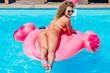© Тарас Нагирняк - Blonde girl with fit body in the pool on an inflatable pink flamingo in a bathing suit. Sexual woman.