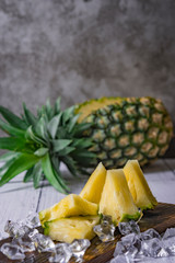 Wall Mural - Pineapple cocktail or juice with ice and pineapples on a dark background