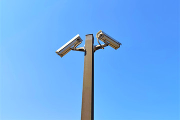 Two security cameras against the blue sky are monitoring, copy space.