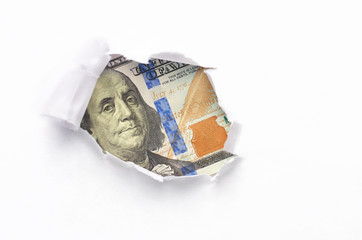 Portrait of Benjamin Franklin, is depicted on the banknote one hundred dollars USA peeking through broken sheet white of paper