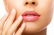 © Julia - Close up beautiful  Lips. Beauty Fashion woman lips with natural Makeup. shine lipstick. isolated. Closeup mouth Nude Colors lacquered model touches her lips with her hand. Make up.