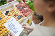 © Seventyfour - High angle closeup of unrecognizable young woman holding shopping list while buying groceries at farmers market, copy space