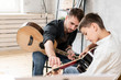 © stock28studio - Two brother playing guitar. Older brother teaches younger one to play chords correctly
