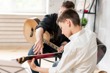 a personal tutor explains to his young student how to play studied chord correctly. musical educatio