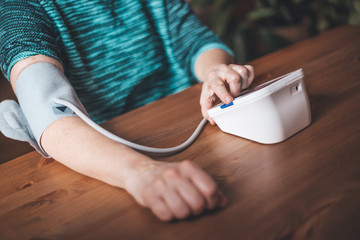 Woman health check blood pressure and heart rate at home with digital pressure, health and medical concept (color toned image)