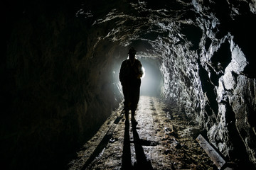 Canvas Print - Creepy backlit human silhouette inside dark abandoned mine