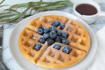 Wall Mural - Belgian Waffle with Blueberries and Maple Syrup, Dusted with Powdered Sugar, Flay Lay on Marble Background, Copy Space