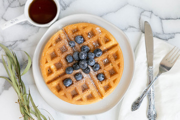 Wall Mural - Belgian Waffle with Blueberries and Maple Syrup, Dusted with Powdered Sugar, Flay Lay on Marble Background, Copy Space