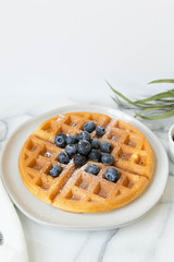 Wall Mural - Belgian Waffle with Blueberries and Maple Syrup, Dusted with Powdered Sugar, Flay Lay on Marble Background, Copy Space