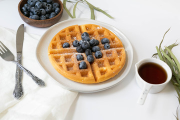 Wall Mural - Belgian Waffle with Blueberries and Maple Syrup, Dusted with Powdered Sugar, Flay Lay on White Background, Copy Space
