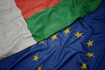 waving colorful flag of european union and flag of madagascar.