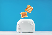 Roasted Toast Bread Popping Up Of Toaster With Blue Wall