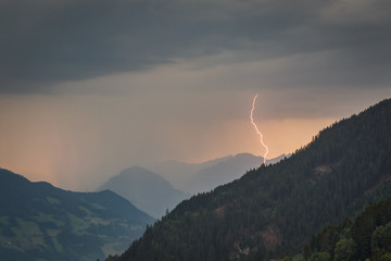 Wall Mural - lightning bolt strikes in a valley from an alpine evening thunderstorm