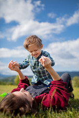 Wall Mural - mother have a fun with a son on a meadow in mountains