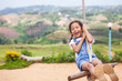 Happy asian child girl having fun to play on wooden swings in playground with beautiful nature