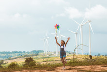 Cute Asian Child Girl Is Running And Playing With Wind Turbine Toy  With Fun In The Wind Turbine Field