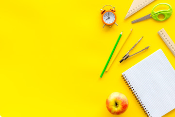 Wall Mural - Back to school with stationary, apple, notebook and alarm clock on yellow student desk background top view mock-up